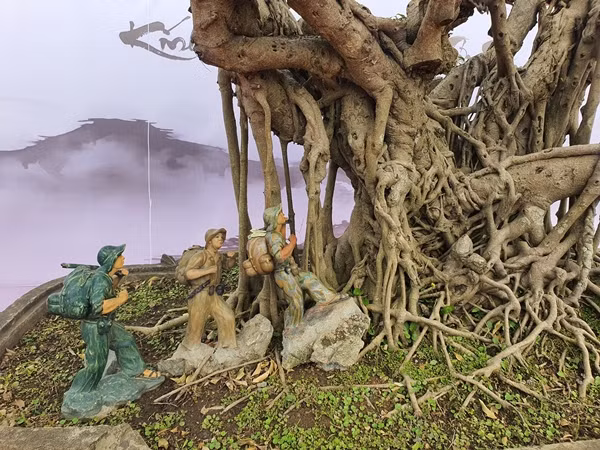 Dưới gốc cây, chủ nhân có trang trí hình ảnh các chú bộ đội đang hành quân với balo và khẩu súng vác trên vai. Ảnh: Người đưa tin