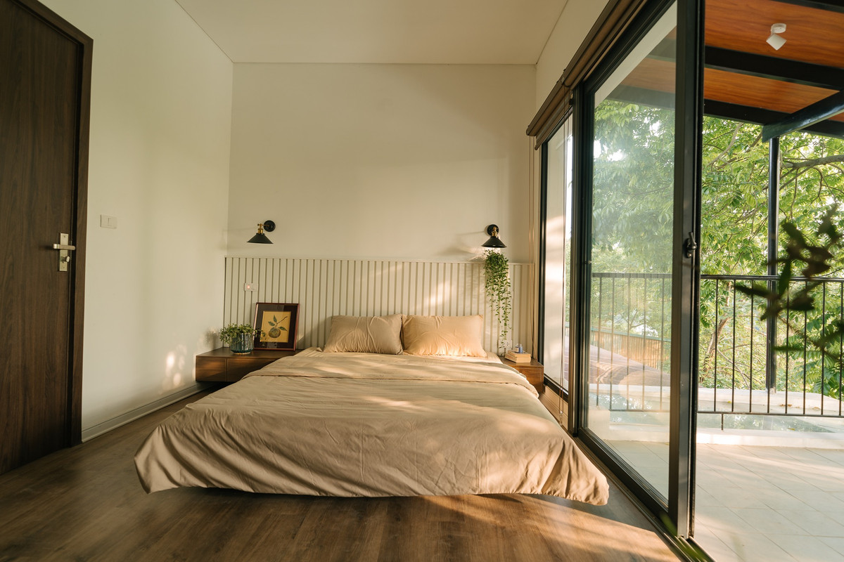 Phòng ngủ ở tầng 2 gam màu ấm cúng, nhẹ nhàng, có ban công rộng rãi. Ảnh: Luke Nguyen Lab