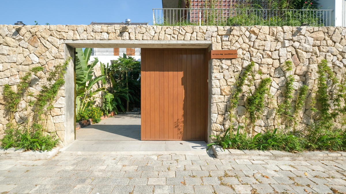 Cổng vào mộc mạc điểm xuyết cây trang trí, hài hoà với tổng thể chung của căn nhà. Ảnh: Kiến trúc Chơn