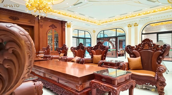 Chính giữa phòng khách là bộ bàn ghế gỗ được chạm khắc tinh xảo theo phong cách cổ điển. Ảnh: chụp màn hình NhaTo