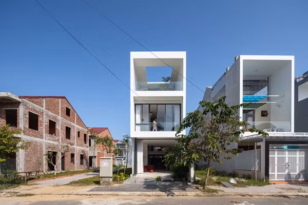 Thay vì tận dụng hết quỹ đất để xây dựng, kiến trúc sư và gia chủ quyết định lùi toàn bộ 4 mặt ngôi nhà, chừa một khoảng đất bao quanh để trồng cây, tạo thảm cỏ xanh mướt. Ảnh: Triệu Chiến