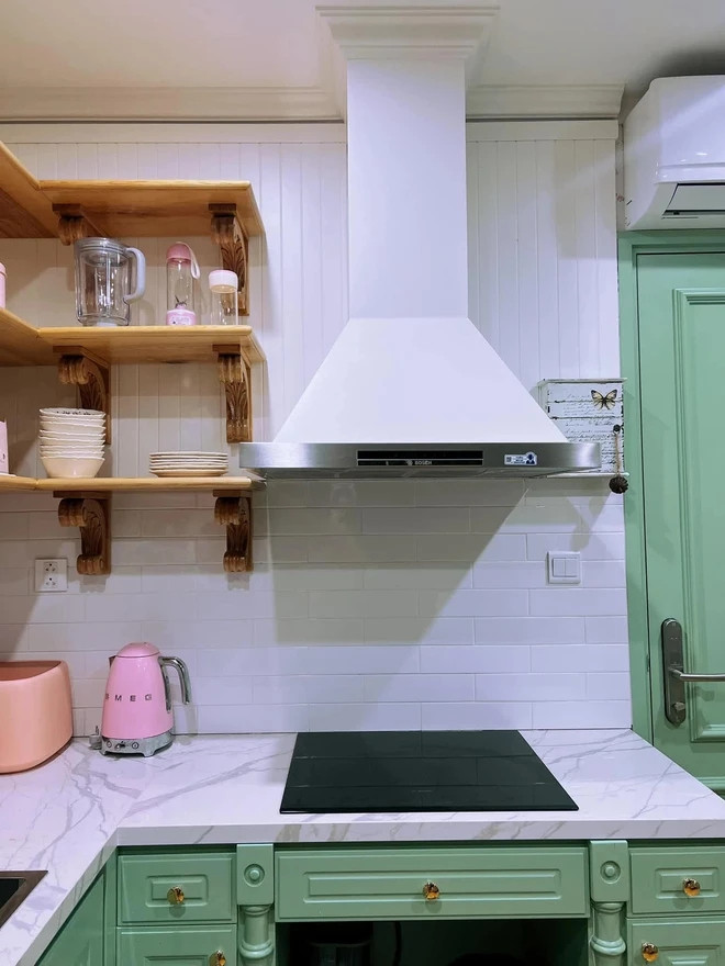 Khu bếp mang lại cảm giác nhẹ nhàng và tươi mới với gam trắng - xanh chủ đạo, được điểm xuyết bởi các món đồ bếp màu hồng và cam. Ảnh: FB Hòa Minzy