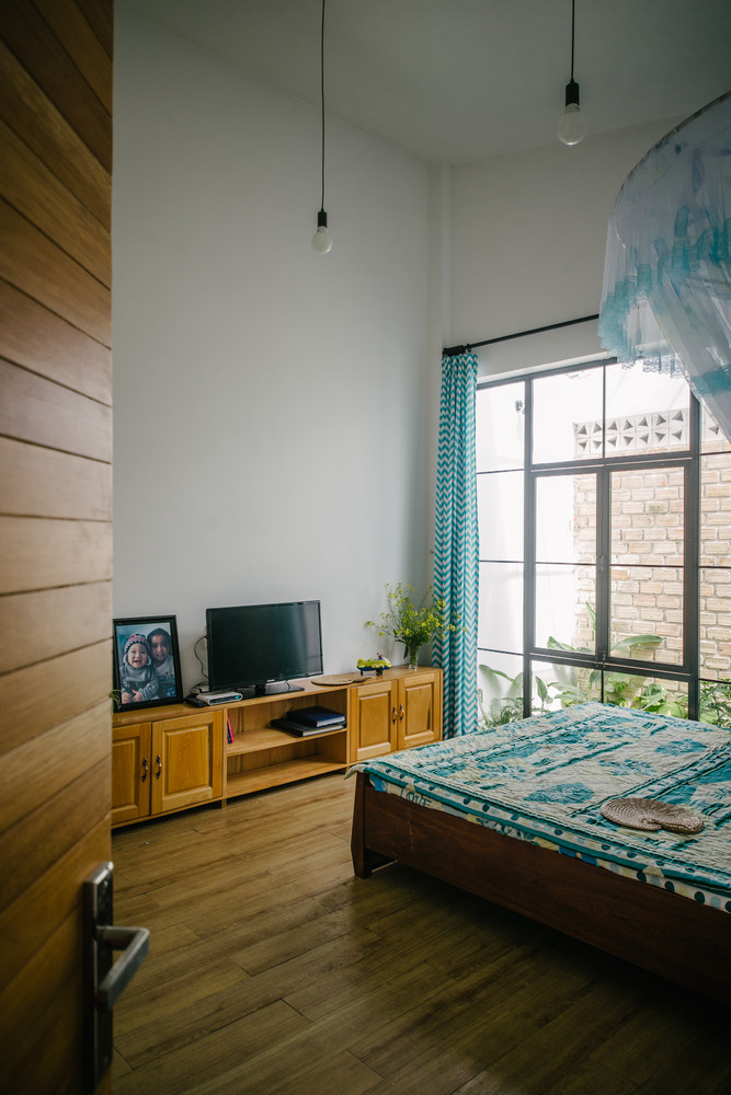 Phòng ngủ đơn giản với khung cửa kính lớn. Ảnh: Khuon Studio