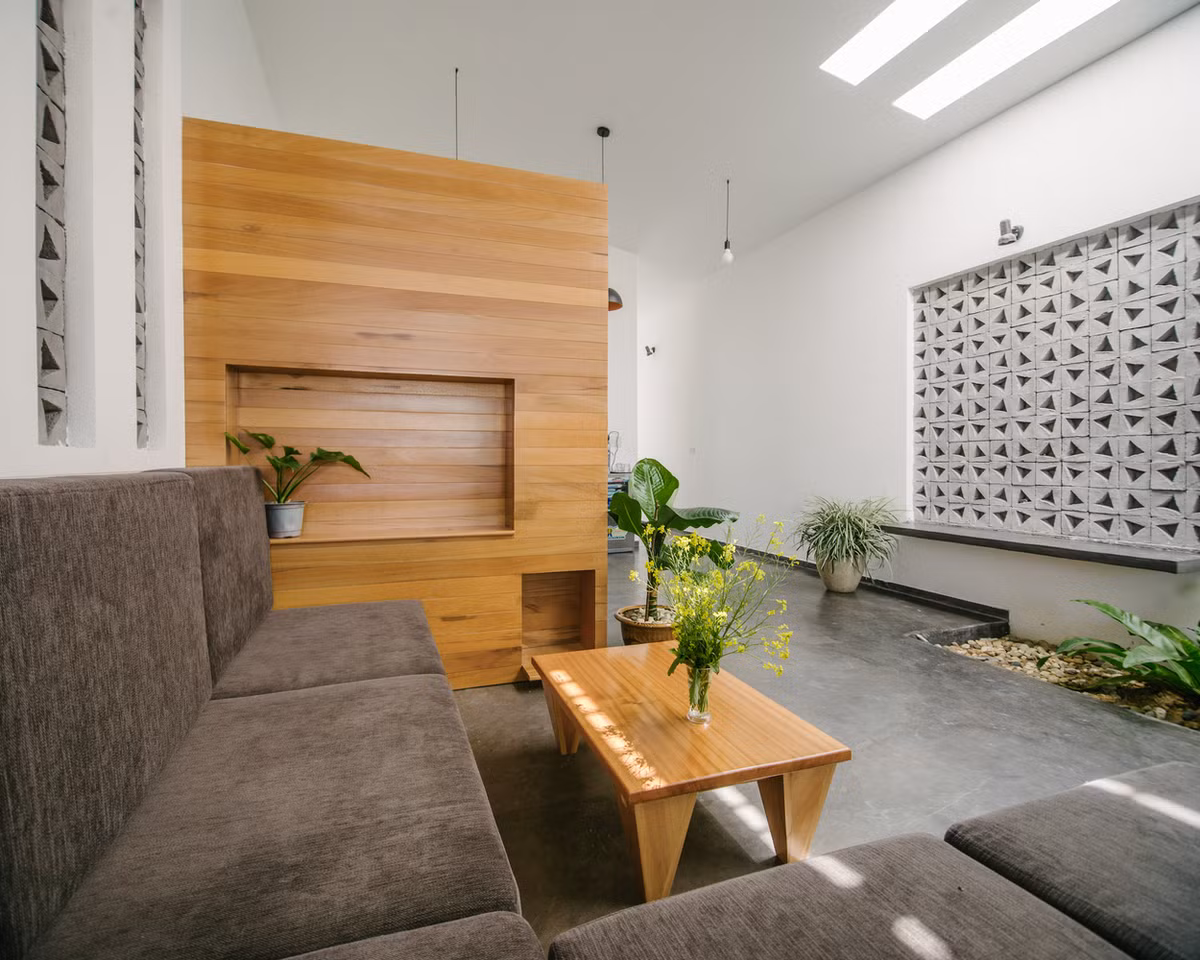  Phòng khách sử dụng nội thất tối giản với chất liệu gỗ thô mộc và sàn xi măng, tạo cảm giác gần gũi. Ảnh: Khuon Studio