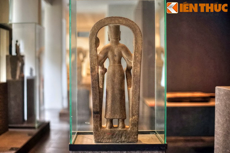 Hiện vật thể hiện hình ảnh một nữ nhân đầu đội mũ trụ, có bốn tay đứng trên bệ liền với một vòng cung đỡ ở phía sau.