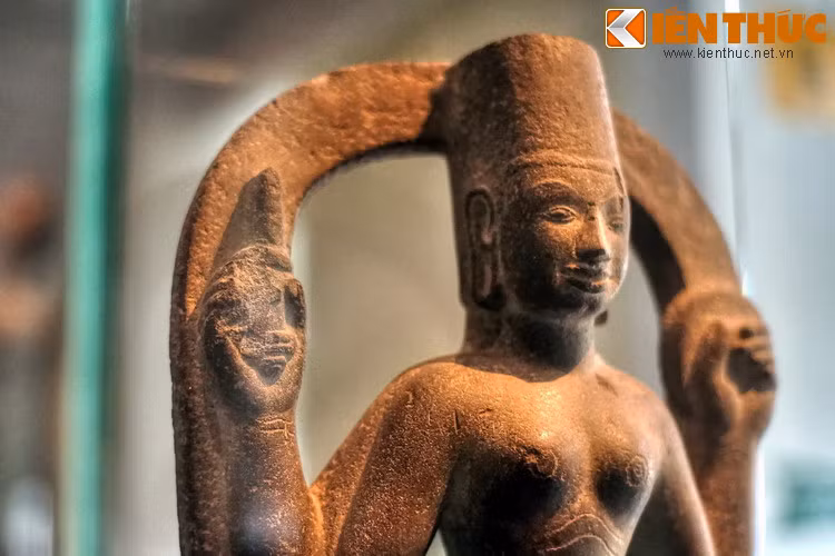 Hai tay sau tượng đưa lên ngang vai, một tay cầm một vật hình đĩa tròn, có thể là gương, tay kia cầm con dao hoặc tù và.