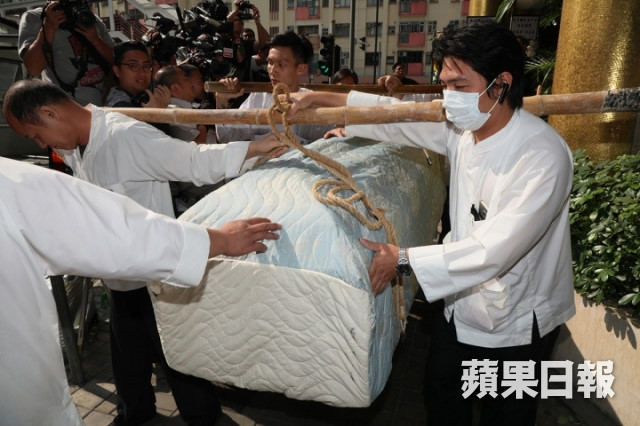 Quan tài của Kim Dung được phủ bằng vài thêu màu xanh nhạt. 6 người đàn ông chịu trách nhiệm đỡ linh cữu lên xe tang.