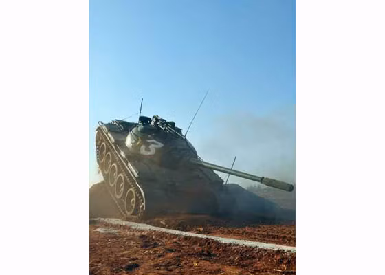 Một chiếc xe tăng loại T-54/55 đang hành tiến vượt địa hình ghồ ghề.