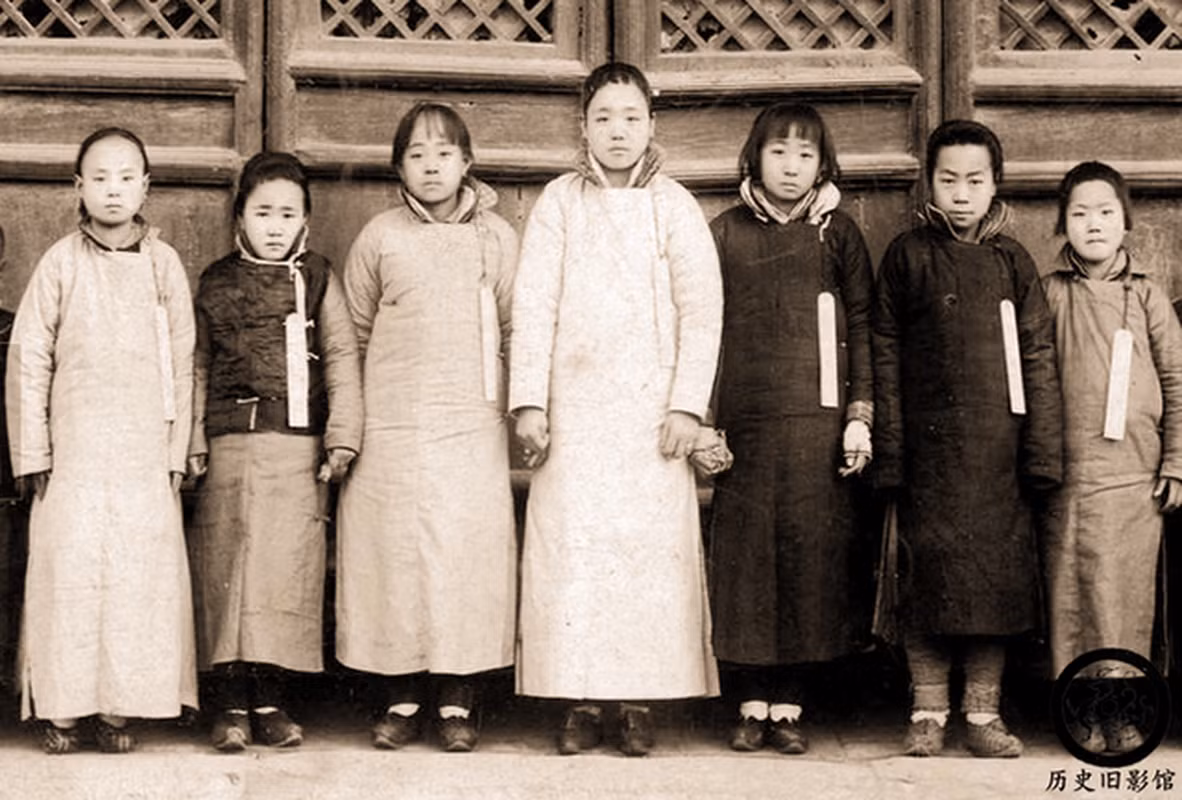 Những bé gái đeo một tấm thẻ gỗ trên người ghi tên tuổi, quê quán khi tham gia tuyển chọn cung nữ trong Tử Cấm Thành. Theo quy định của hoàng tộc nhà Thanh, những bé gái này đều dưới 13 tuổi. Bức ảnh chụp cho thấy, những đứa trẻ này có dung mạo bình thường.