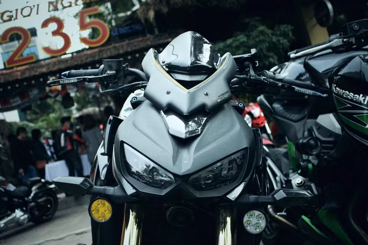 Ngay từ phần đầu, chiếc Z1000 đã được chủ xe lắp cho chiếc kính chắn gió Puig phiên bản kỷ niệm 32 năm đặc biệt. Có số thứ tự 32/50, những đường nét của chiếc kính chắn gió này đã "ăn nhập" hoàn hảo với phần đầu phong cách Sugomi của Z1000. Nằm bên dưới cặp xi-nhan của xe là cặp đèn LED L4 chiếu sáng tăng cường trong đêm tối.