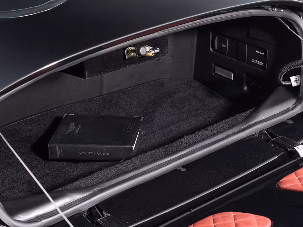 Dù là một mẫu coupe nhưng ở phía sau, DB7 Zagato vẫn có khoang hành lý tương đối tiện dụng, đủ chỗ chứa 2 vali du lịch cỡ lớn. Đẳng cấp siêu sang của chiếc xe được thể hiện ở phần đệm lót cửa khoang hành lý cũng được bọc Alcantara và da đỏ chần chỉ như các ghế ngồi trong cabin.