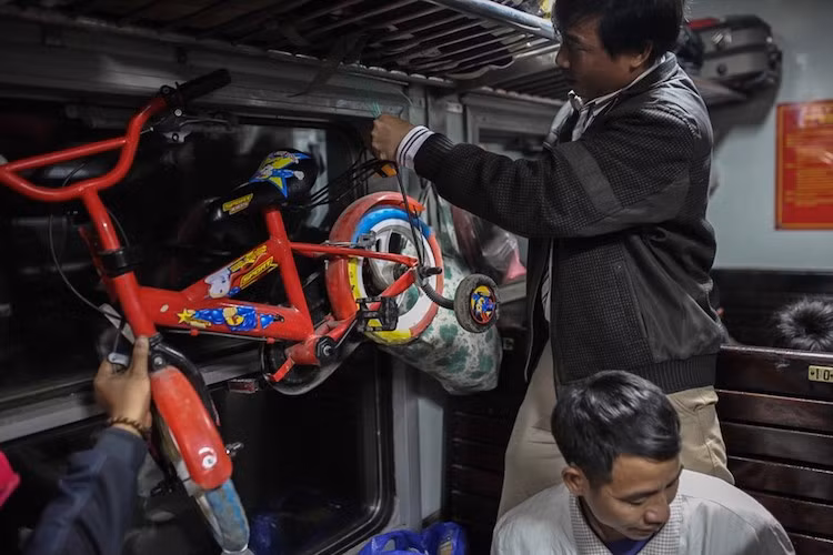 Đi tàu hỏa, khách có thể mang theo nhiều đồ dùng có kích thước lớn. Tại ga Đồng Hới, vừa bước lên toa, người đàn ông này tận dụng không gian trống treo chiếc xe đạp để mang vào miền Nam cho con.