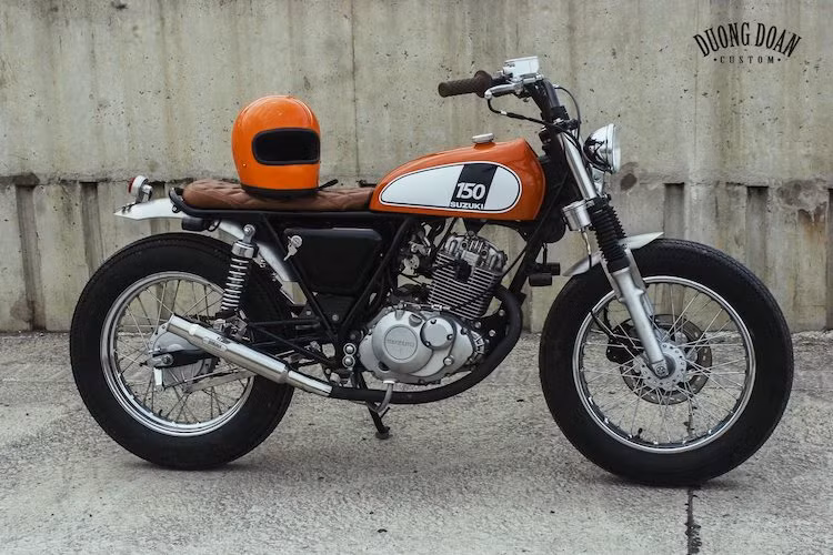 Để phù hợp với phong cách cổ điển của toàn thể bản độ, cặp ốp che hệ thống điện và ắc quy hai bên thân xe cũng đã được gò lại. Khối động cơ SOHC xi-lanh đơn 150 cc làm mát bằng không khí, hộp số 6 cấp phun nhiên liệu điện tử của EN150A vốn nổi tiếng vì sự bền bỉ, chính vì vậy Duong Doan Design đã giữ nguyên chi tiết này trên chiếc xe.