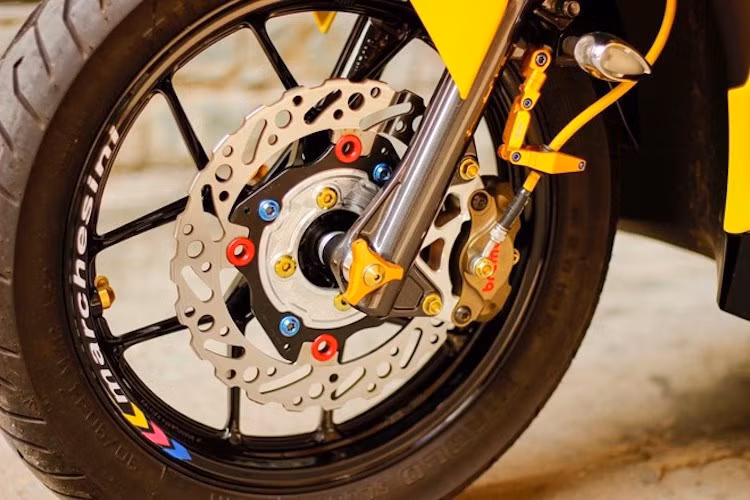 "Dàn chân" của chiếc xe ga Airblade độ này nổi bật với bộ mâm đúc 5 cánh thể thao từ Honda Vario dành cho thị trường Indonesia, cùng với các món đồ "kiểng" khác như đĩa Braketech, heo Brembo Billet, pát kẹp dây dầu DMV và dàn ốc Proti kết hợp với Pro Bolt.