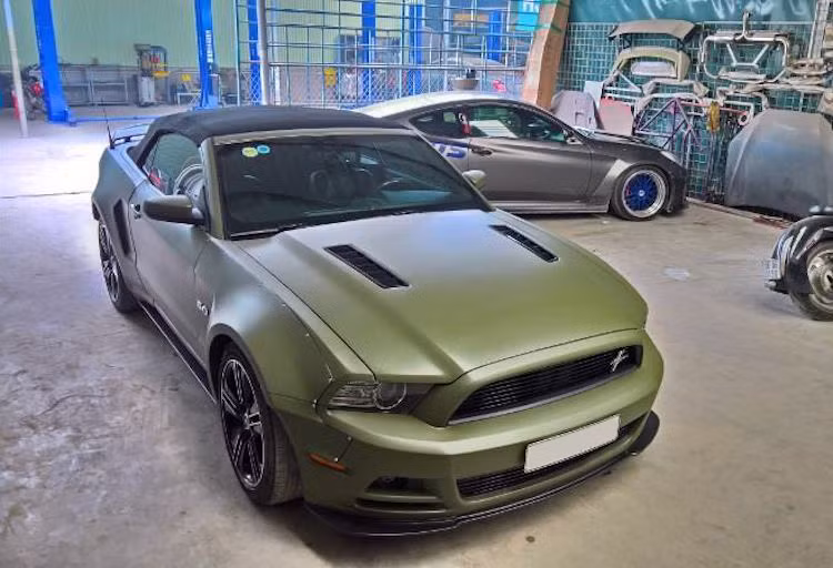 Để "làm mới" chiếc Mustang GT Convertible thế hệ thứ 5 của mình trước thềm năm mới, một chủ xe ở Hà Nội đã "gửi gắm" chiếc xe tới xưởng độ QS Performance để tiến hành "khoác áo mới" - thay đổi màu sơn và nâng cấp ngoại thất.