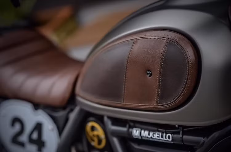Để tăng chất cổ điển cho chiếc xe, thay vì 2 miếng ốp bằng nhôm ở hai bên bình xăng nguyên bản, Mugello đã thay bằng những miếng ốp da được khâu thủ công một cách khéo léo, như những chiếc túi da bò của các quý ông.
