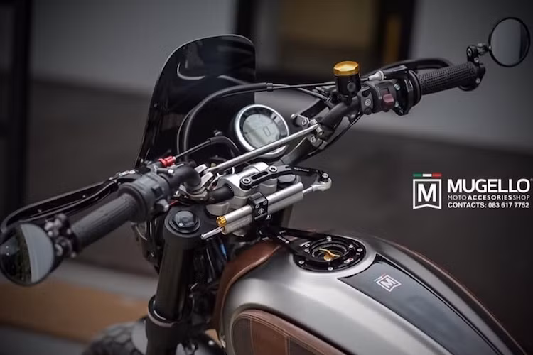 Nằm phía trên tay lái của xe cũng là một loạt các "đồ chơi" như thanh giằng ghi-đông theo phong cách "cào cào", trợ lực cổ Ohlins với pát bắt của Ducabike. Trong khi đó phía dưới bình xăng là nắp xăng đóng mở nhanh CNC của hãng TWM Racing.