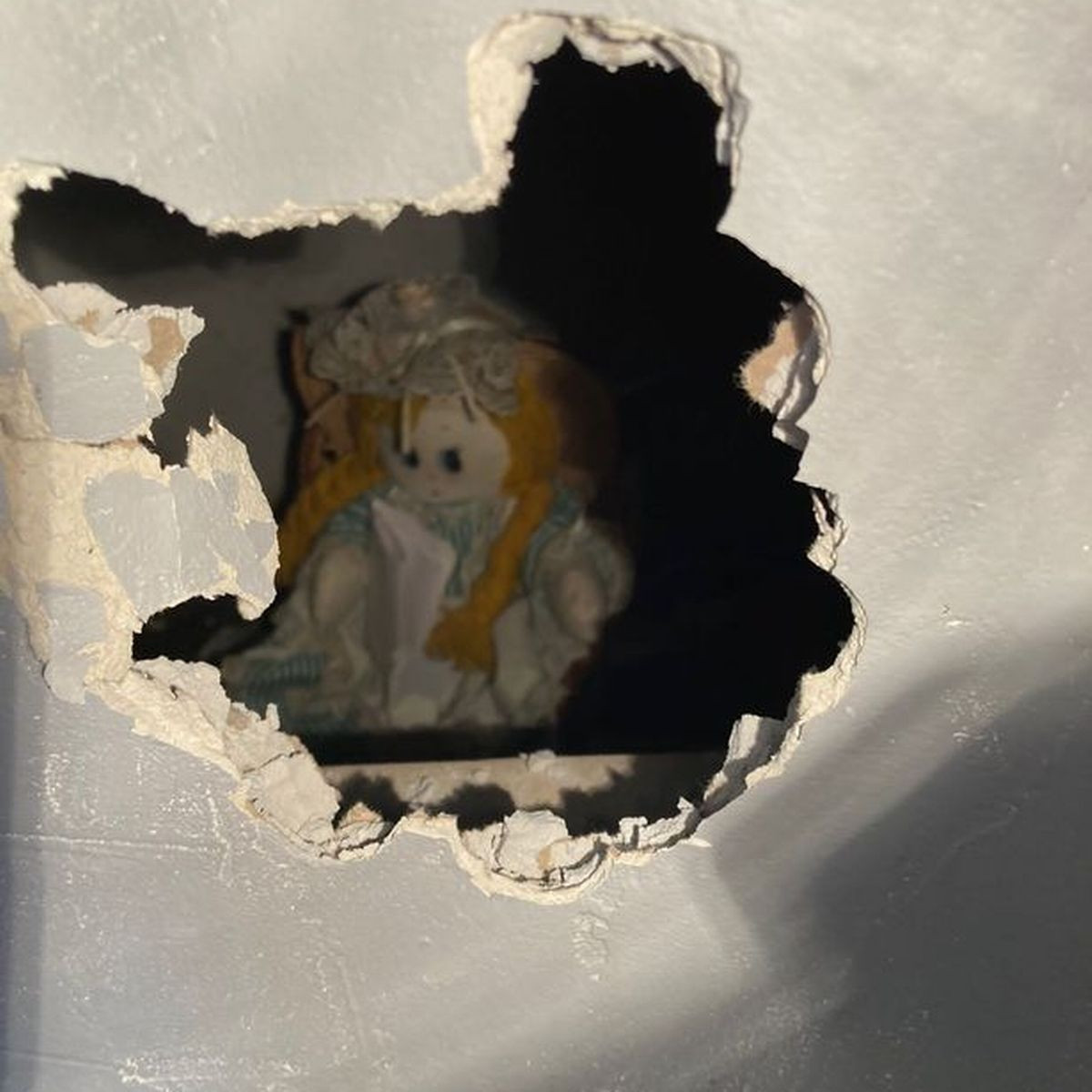 Chủ nhà người Anh phát hiện một con búp bê kỳ lạ rách rưới được giấu sau bức tường. Nó mặc chiếc váy có họa tiết sọc, đội mũ lưỡi trai, trên tay còn ôm một tờ giấy khiến anh không khỏi tò mò. Ảnh: Dailymail