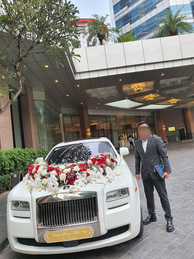 Đầu tiên là siêu xe Roll Royce không dưới 20 tỷ được che biển số xe thành bảng đề tên cô dâu chú rể. Trên xe được trang trí hoa trắng và đỏ truyền thống, phối cùng baby tinh khôi, tạo nét sang trọng và lãng mạn.