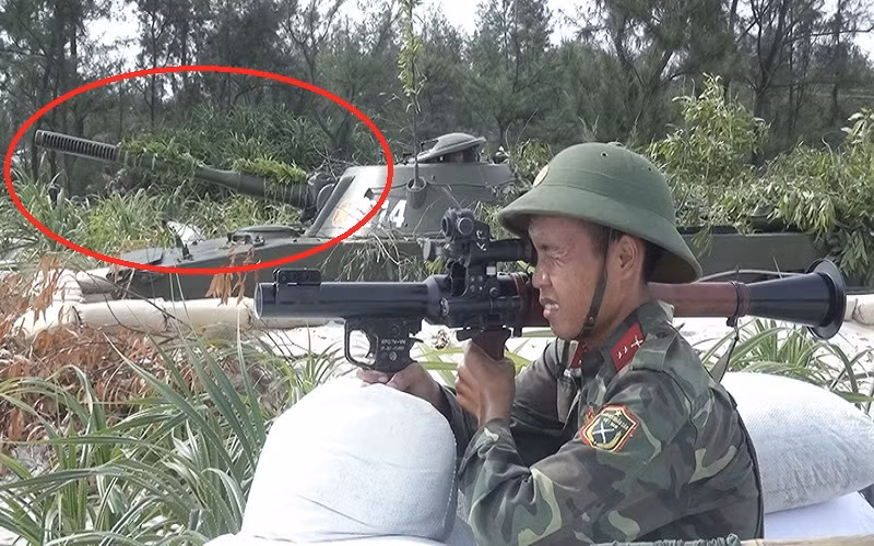 Và dựa trên tìm hiểu của Kiến Thức, khẩu pháo “lạ” trên PT-76 tham gia diễn tập ở Quảng Trị hóa ra có một lai lịch khá đặc biệt khi nó chính là tiền thân của pháo D-56TS hiện nay và có tên mã là D-56T. Trong ảnh khoanh đỏ chính là pháo D-56T với thiết kế giảm giật đầu khác biệt hoàn toàn so với D-56TS. Nguồn ảnh: Báo Quảng Trị