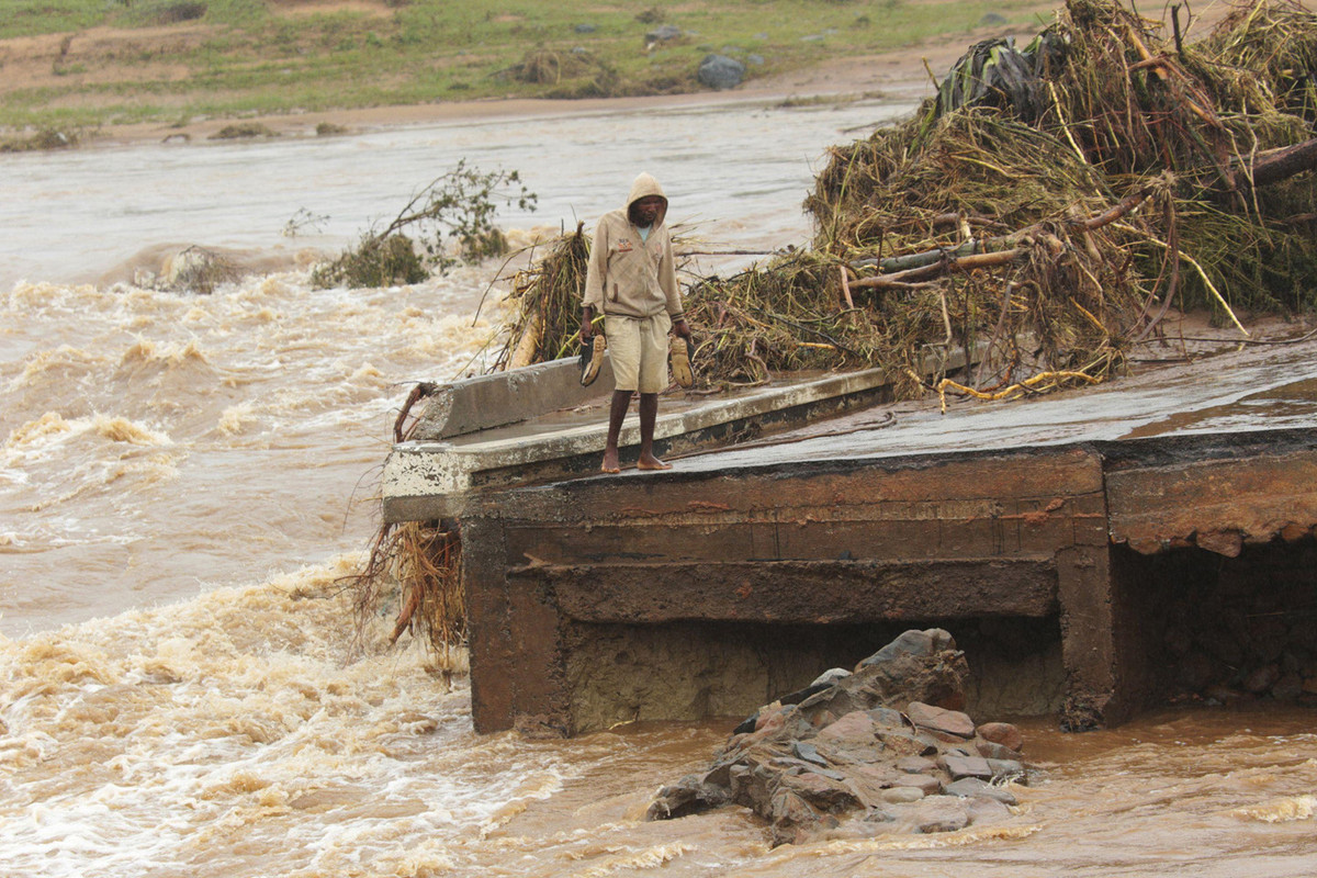 Một người đàn ông đứng bên rìa cây cầu bị sập ở Chimanimani, cách Harare, Zimbabwe khoảng 600 km về phía đông nam. "Thực sự rất tàn khốc. Hôm qua, chúng tôi đã thực hiện cuộc khảo sát trên không và thấy mọi người trên mái nhà và trên cành cây. Nước vẫn đang dâng cao và chúng tôi đang cố gắng hết sức để cứu càng nhiều người càng tốt", bà Caroline Haga của Hội Chữ thập đỏ nói với AP. Ảnh: AP.