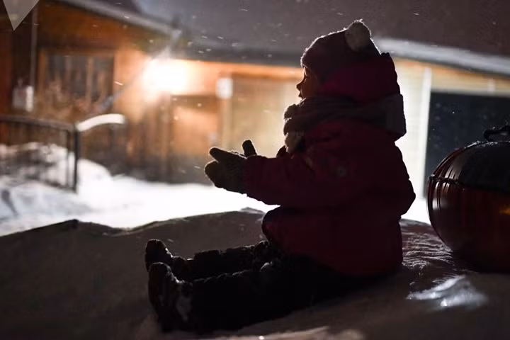 Nụ cười một bé gái mặc đồ rất ấm áp khi chơi đùa với tuyết.