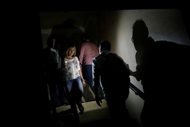Dùng ánh sáng từ điện thoại di động để đi lại trên cầu thang của tòa nhà ở thủ đô Caracas lúc mất điện vào hôm 31/7.
