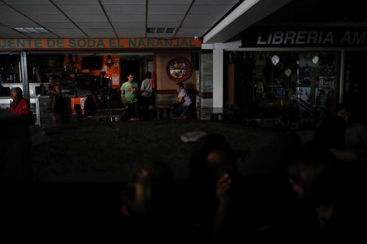 Người dân nói chuyện phía trước một nhà hàng tại một trung tâm mua sắm khi đợi có điện trở lại, hôm 31/7 ở thủ đô Caracas.