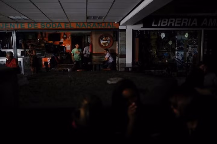 Người dân nói chuyện phía trước một nhà hàng tại một trung tâm mua sắm khi đợi có điện trở lại, hôm 31/7 ở thủ đô Caracas.