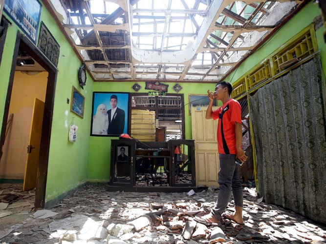 Một thanh niên ngậm ngùi khi đứng trước ngôi nhà tan hoang của mình.