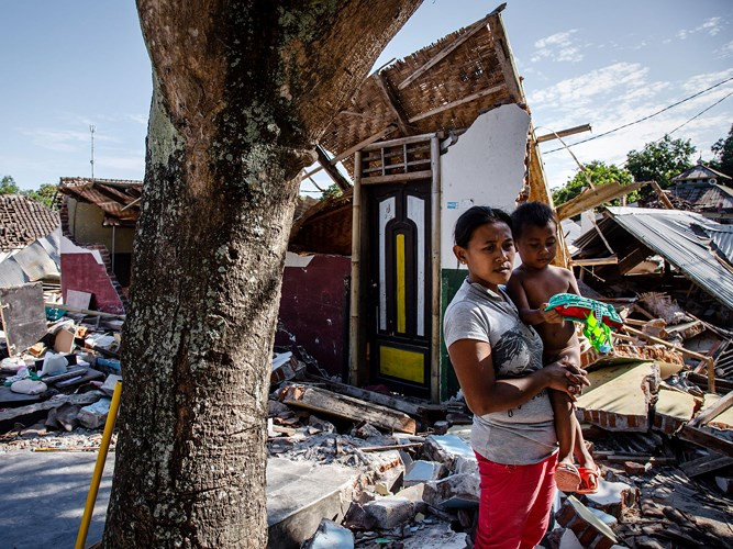 Một người phụ nữ và con trai đứng trước ngôi nhà của họ giờ chỉ còn là đống đổ nát.