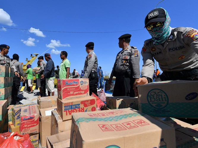 Cảnh sát và các tình nguyện viên Indonesia chuyển các nhu yếu phẩm cho người dân trong khi chính quyền tiếp tục sơ tán các du khách trên đảo Gili Trawangan gần đó tới nơi an toàn.