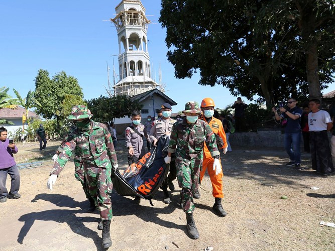 Các nhân viên cứu hộ đang cố gắng đưa thi thể một nạn nhân ra ngoài sau khi nhà thờ Hồi giáo Jabal Nur đổ sập do động đất. Vùng phía bắc của Lombok bị tàn phá nặng nề với hàng nghìn tòa nhà đổ sập và nhiều người thiệt mạng.