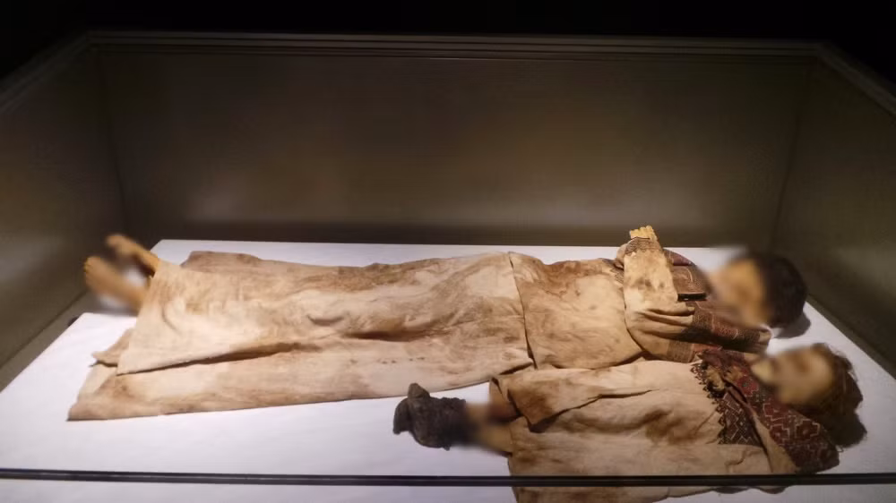 Yasmine mặc 3 chiếc váy (bao gồm 1 chiếc màu xanh lam, 1 chiếc màu be và chiếc cuối cùng màu be sẫm), được đặt trong tư thế nằm ngửa, đầu tựa vào một phiến đá nhẵn. Đứa trẻ này có đeo khuyên tai, vòng cổ. Gần xác ướp của bé gái có một lọn tóc sẫm màu hơn, lá nguyệt quế, quả hạnh, quả óc chó, vỏ tỏi và hành tây.