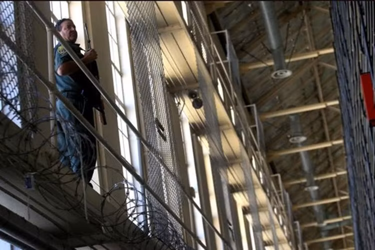 Một cảnh sát canh gác ở khu biệt giam với khẩu súng tiểu liên.