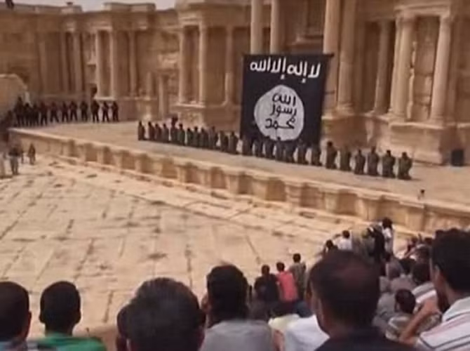 Vụ hành quyết này được tiến hành trước một đám đông những người đàn ông và một số trẻ nhỏ ngồi xem trên các ghế của nhà hát cổ của thành phố Palmyra ở đông bắc Syria.