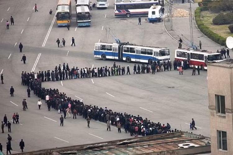 Xếp hàng là một thói quen cần thiết của công dân Triều Tiên trong việc mua vé tàu xe hay nhu yếu phẩm. Trong ảnh là cảnh xếp hàng rồng rắn tại một bến xe buýt ở thủ đô Bình Nhưỡng. (Nguồn: ATI)