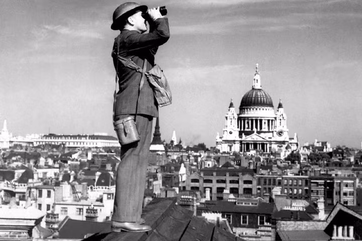 Một quân nhân đứng trên mái một tòa nhà ở London, Anh, để theo dõi máy bay địch. Nền ảnh là nhà thờ Saint Paul. Đức chưa đổ bộ lên Anh mà dùng không quân đánh phá ác liệt nước này. Ảnh: Bộ Quốc phòng Đức