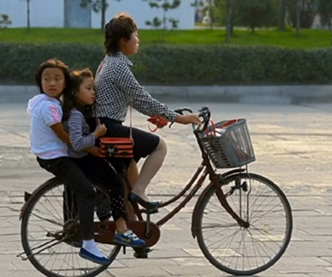 Đưa con đi học. Xe đạp vẫn là phương tiện đi lại khá phổ biến ở CHDCND Triều Tiên.
