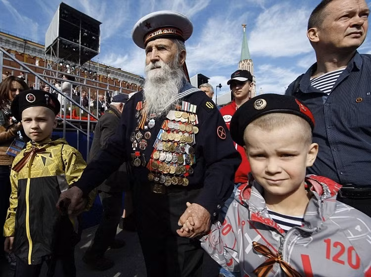 Trong ảnh là một cựu chiến binh hải quân dắt tay hai em bé tham dự lễ kỷ niệm Ngày Chiến thắng trên Quảng trường Đỏ.