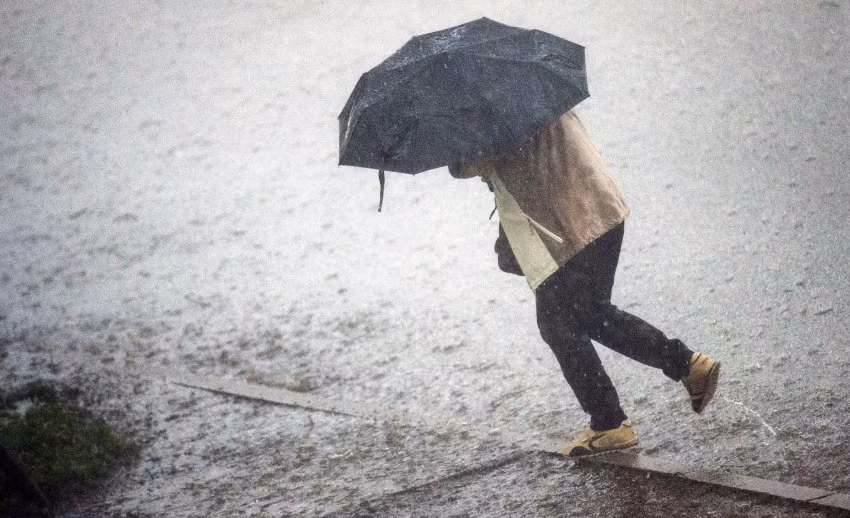 Một phụ nữ cố băng qua đường, khi giông bão mang mưa như trút nước xuống đường phố Hamburg.