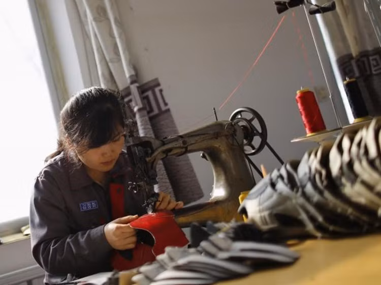 Một nữ công nhân làm việc trong xưởng gia công giày thể thao ở một ngôi làng ngoại ô thành phố Dandong.