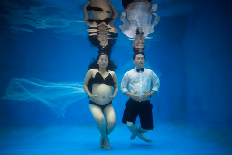 Cặp vợ chồng Trung Quốc khoe bụng bầu trong bể kính kỷ niệm một năm ngày cưới. Ảnh: Sputnik