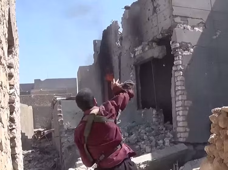 Phiến quân IS ném lựu đạn về phía đối phương đang ẩn nấp trong đống đổ nát của thành phố Ramadi, sau nhiều tuần chiến tranh.