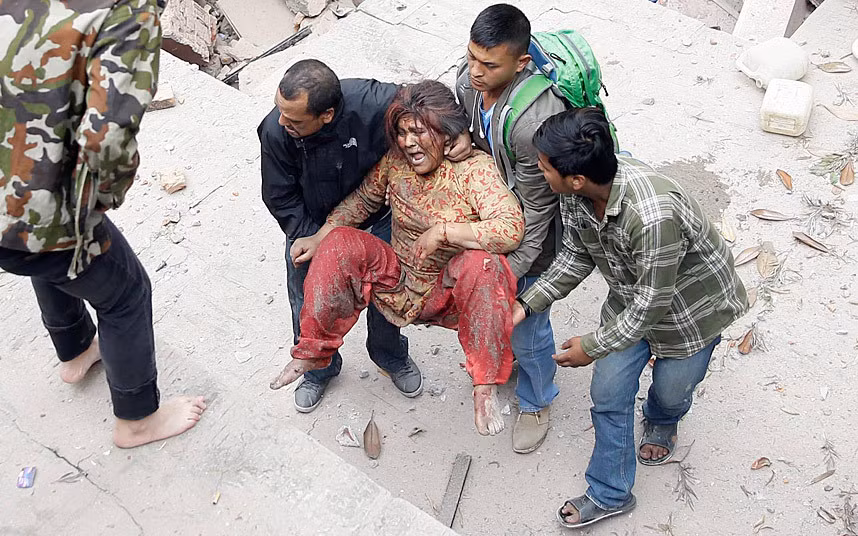 Nhân viên cứu hộ đưa một phụ nữ ra khỏi ngôi nhà bị đổ sập ở Kathmandu.