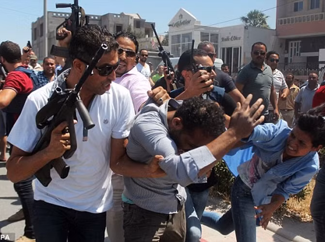 Lực lượng an ninh Tunisia dẫn nghi can khủng bố bị bắt đi trên đường phố Sousse và tên này đã bị một phụ nữ xông vào đánh đập.