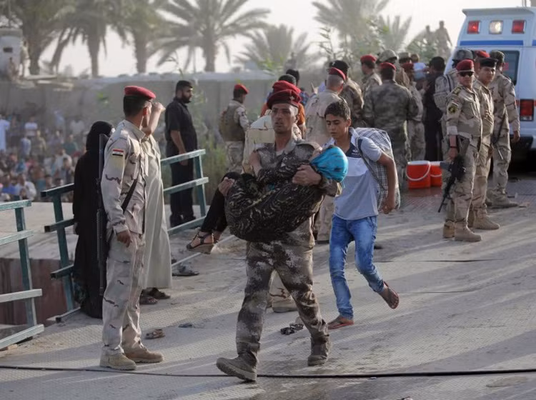 Binh lính Iraq bế một phụ nữ đã kiệt sức sau chặng đường chạy loạn cả trăm cây số từ Ramadi đến Baghdad.