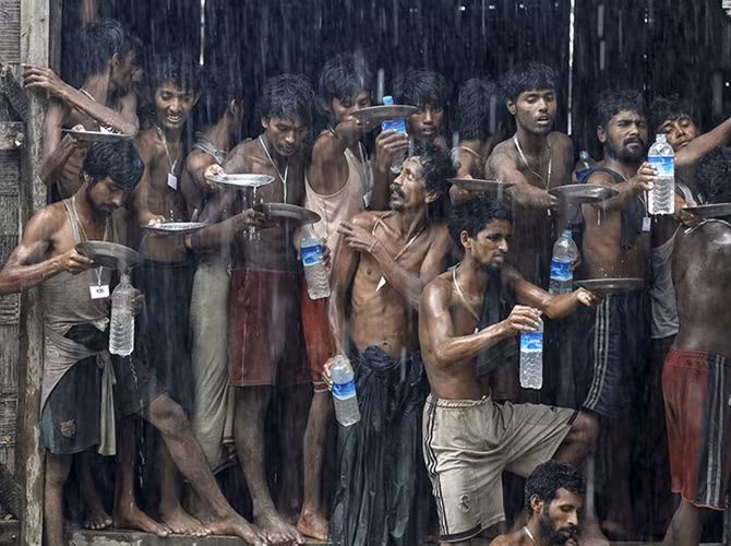 Những người di cư này đã được tìm thấy ở chiếc thuyền lênh đênh trên biển. Quá ám ảnh bởi tình trạng đói khát vừa qua, họ đua nhau hứng nước mưa tại một trại tị nạn tạm thời gần cảng Kanyin Chaung, thị trấn Maungdaw, bang Rakhine, Myanmar.