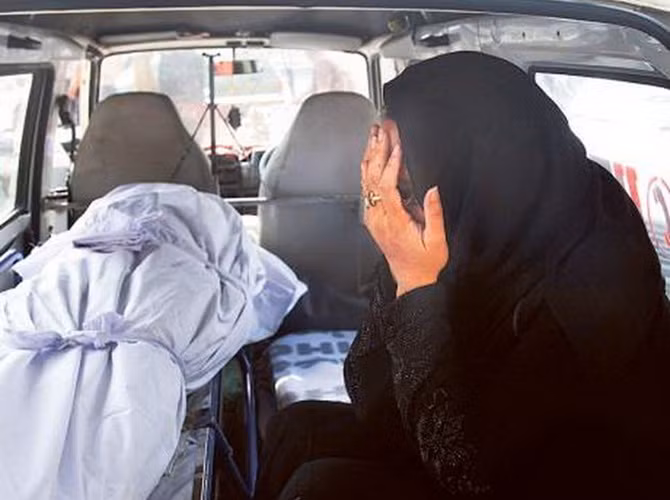 Một phụ nữ khóc lóc trong xe cấp cứu bên cạnh thi thể người thân chết do nắng nóng.