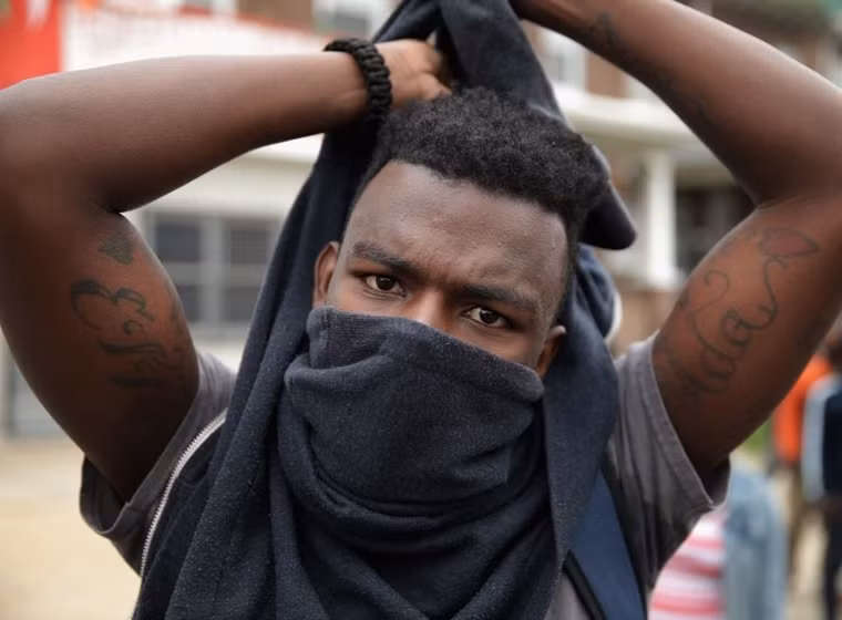 Một thanh niên da màu bịt khăn ướt đề phòng cảnh sát bắn hơi cay.